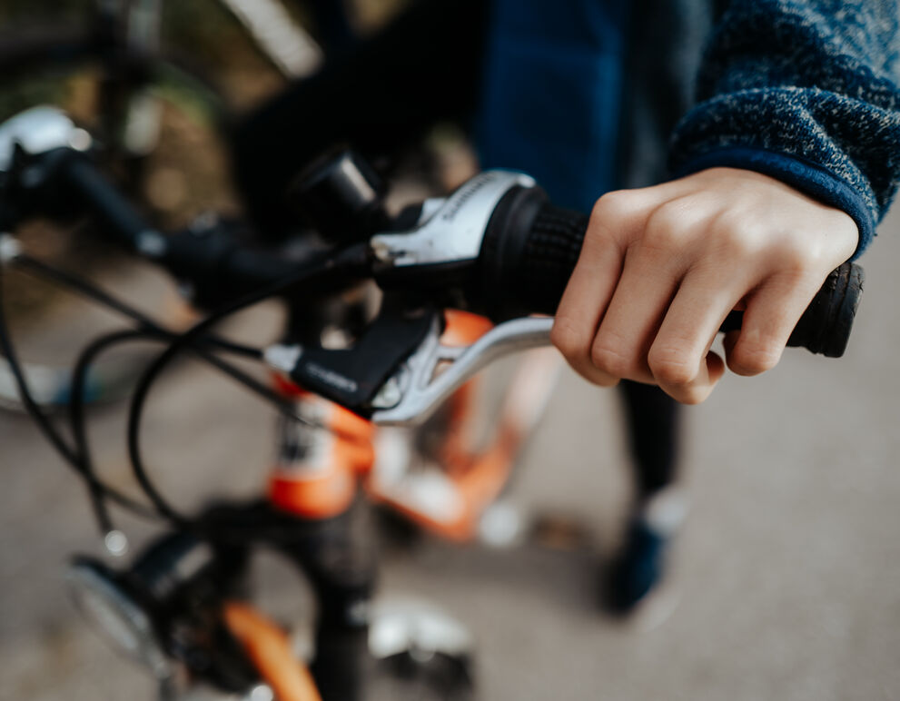 Nahaufnahme von Fahrradlenker, der von Kinderhänden gehalten wird;
